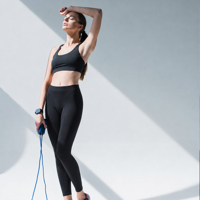 Femme en legging prenant une pose entre deux séances de corde à sauté