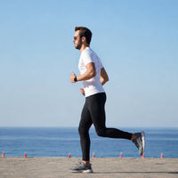 Homme en legging en train de courir au bord de la mer