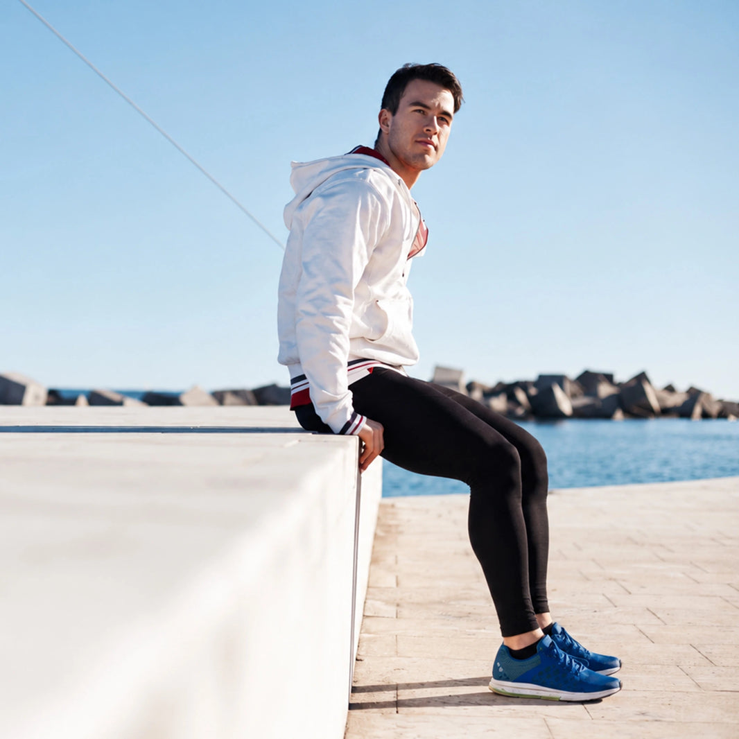 Homme en legging assis au bord de la mer, faisant une pause