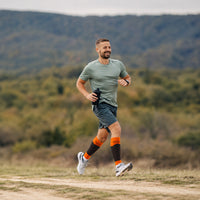 Homme en train de courir sur une route de montagne avec une gourde à la main