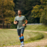 Homme en train de courir sur un chemin de terre avec des manchons de mollets