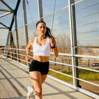 Femme en brassiere de sport blanche courant sur un pont