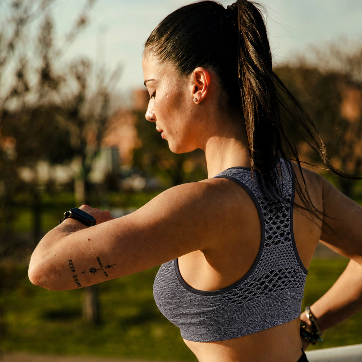 Femme en brassiere de sport grise regardant sa montre pendant sa course