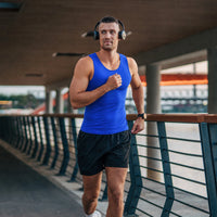 Homme en débardeur bleue de sport faisant un jogging sur un pont