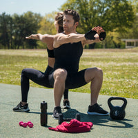 Homme dos à dos avec une sportive en train de faire mutuellement des étirements