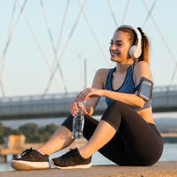 Femme assise après sa session de running en train de boire de l'eau